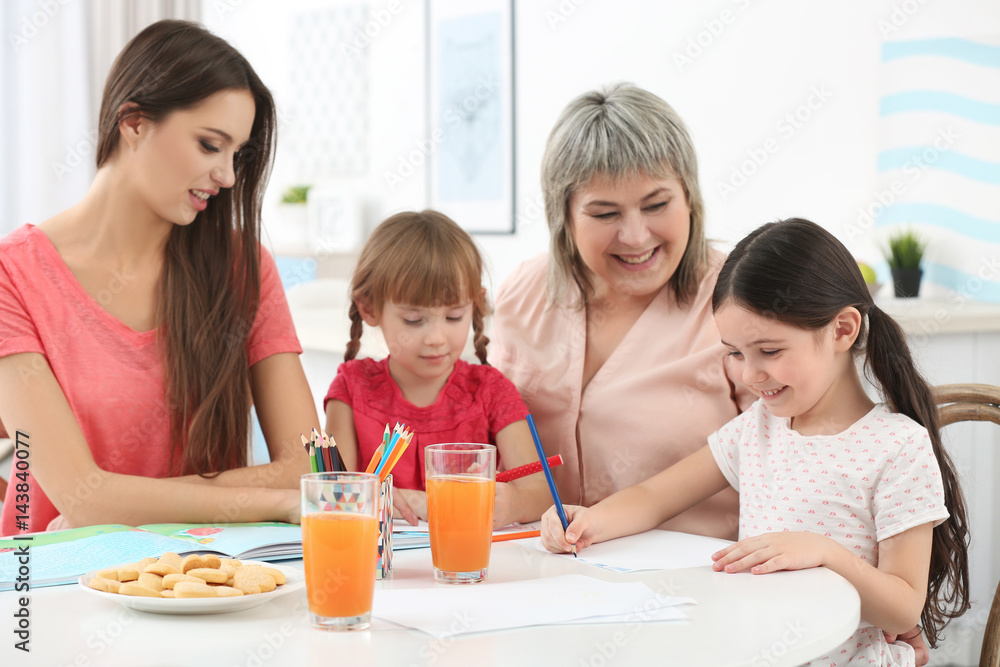 Little girls with grandmother and mother at kitchen table Little girls with grandmother and mother at kitchen table
