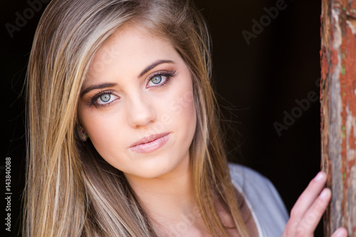 Senior photo of a young woman on a farm wearing farm style clothing