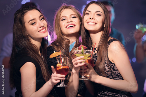 Friends with tasty cocktails at party in night club