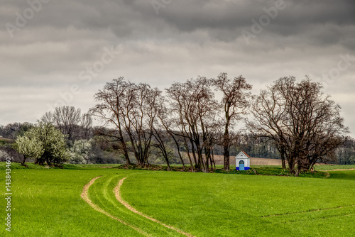 Santa Barbara chapel landscape at spring, South Moravia, Czech Republic. Chapel in a field surrounded by trees with dramatic cloudy skies. High dynamic range.