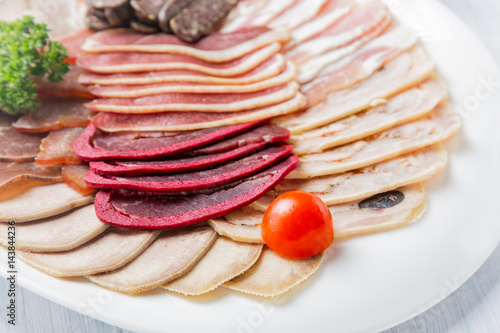 Meat plate with delicious pieces of sliced ham, cherry tomatoes and meat. Close up with selective focus