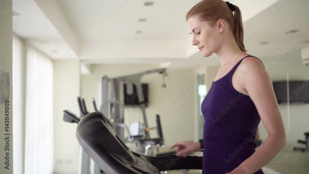 Beautiful fit young woman in a gym doing exercises on a running track. Beautiful fit young woman in a gym doing exercises on a running track.