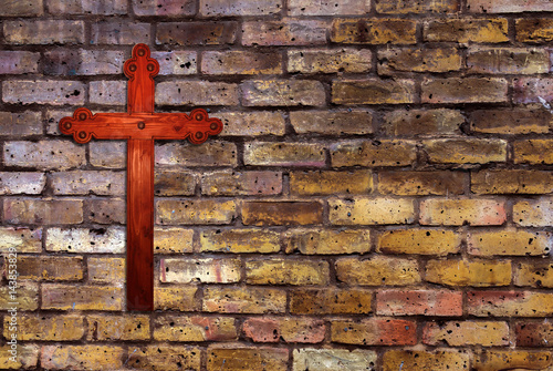 Christian cross hanging on brick wall