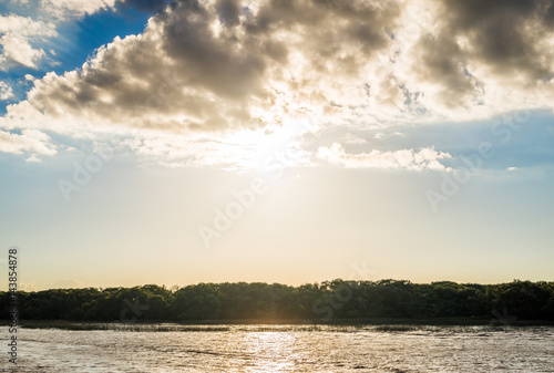 Banks of the Rio de la Plata river (River Plate) with Blue sky with clouds and sun at the sunset