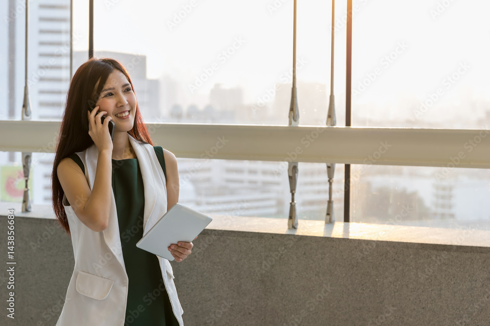 Fototapeta premium Asian Businesswomen holding the tablet and calling the phone with conference Meeting In the modern creative Office, business communication concept