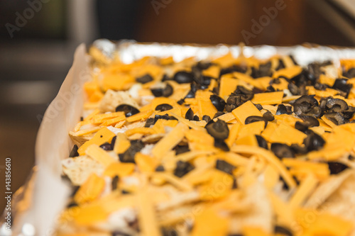 Chips, cheese, and olives on a baking pan.