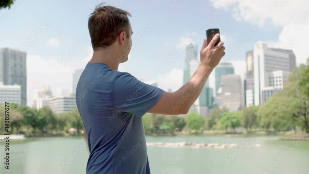 Male runner jogging in park. Fit male sport fitness training. Talking with a friend via Skype Male runner jogging in park. Fit male sport fitness training. Talking with a friend via Skype