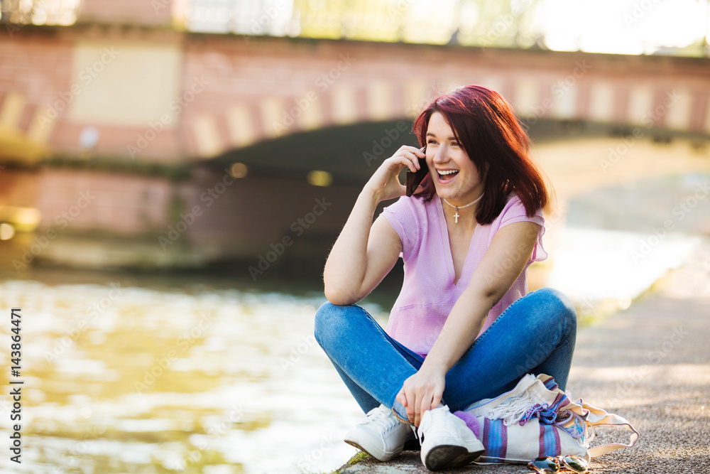 Smart phone, Young smiling woman talking on mobile phone near a river in a spring day.Excited young woman talking on mobile phone near a river in France,Strasbourg.Student.