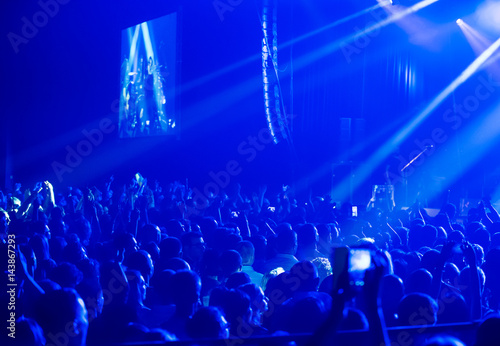 Crowd at concert and blurred stage lights .