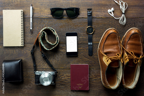 Top view accessories travel with mobile phone,passport,camera,earphones,wallet,notepaper,sunglaases,watch on table wooden with copy space.Travel concept.