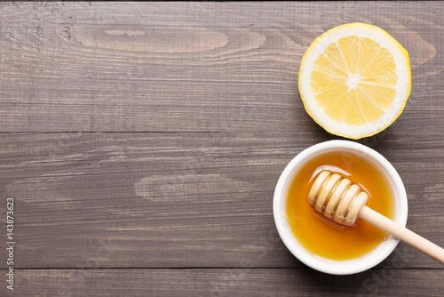 Bowl of sweet honey and lemons on wooden table