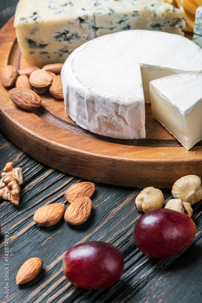 Assorted cheeses with grapes and nuts on a wooden table Assorted cheeses with grapes and nuts on a wooden table