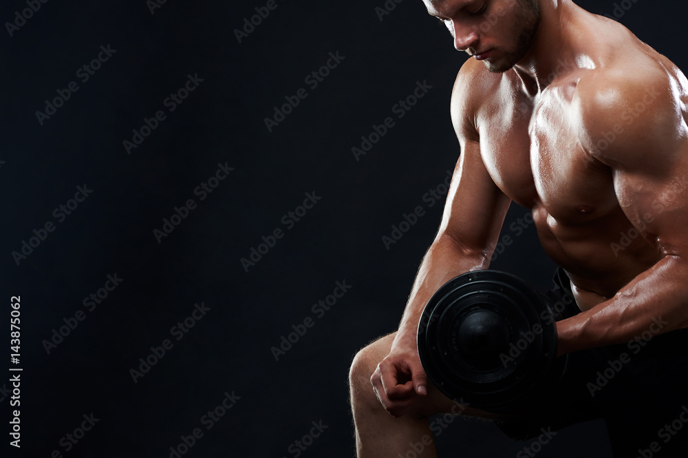 Cropped studio portrait of a handsome young muscular sportsman exercising shirtless showing off his strong sexy ripped body training with dumbbell on black background copyspace fitness gym motivation.
