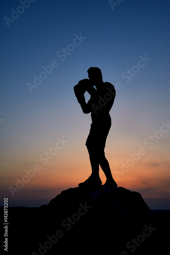 Silhouette of a powerful male boxer training outdoors stunning dusky sky on the background copyspace exercising workout effort endurance combat fighting preparing concentrating motivation
