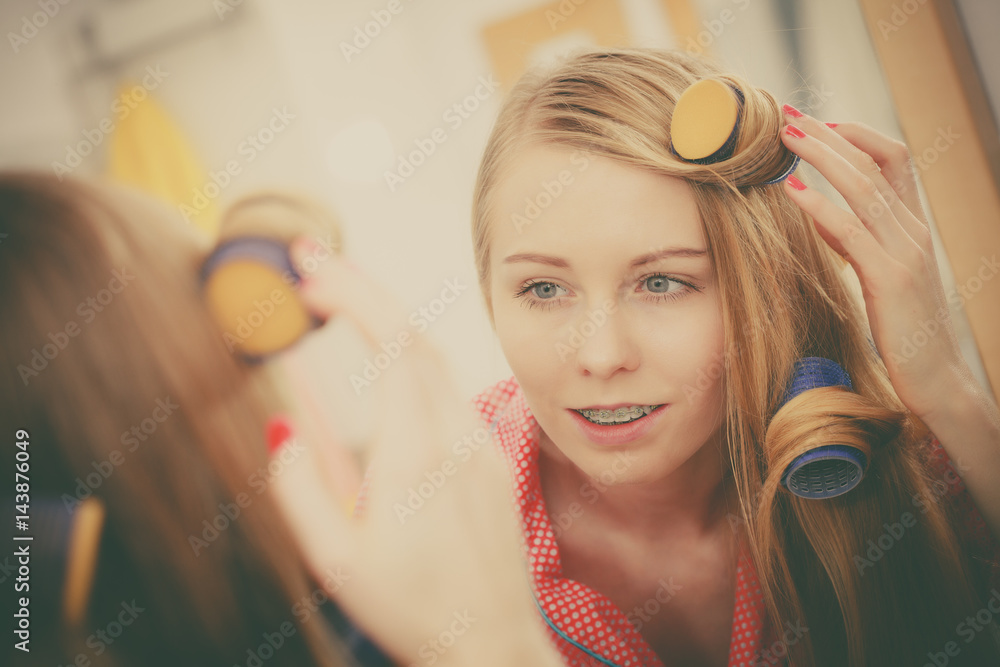 Naklejka premium Woman curling her hair using rollers