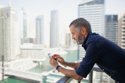 Expat man messaging on mobile at balcony. photo