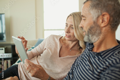 Couple using digital tablet at home.