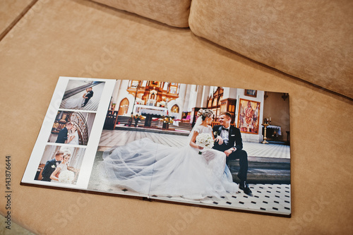 Two open pages of wedding book on sofa.