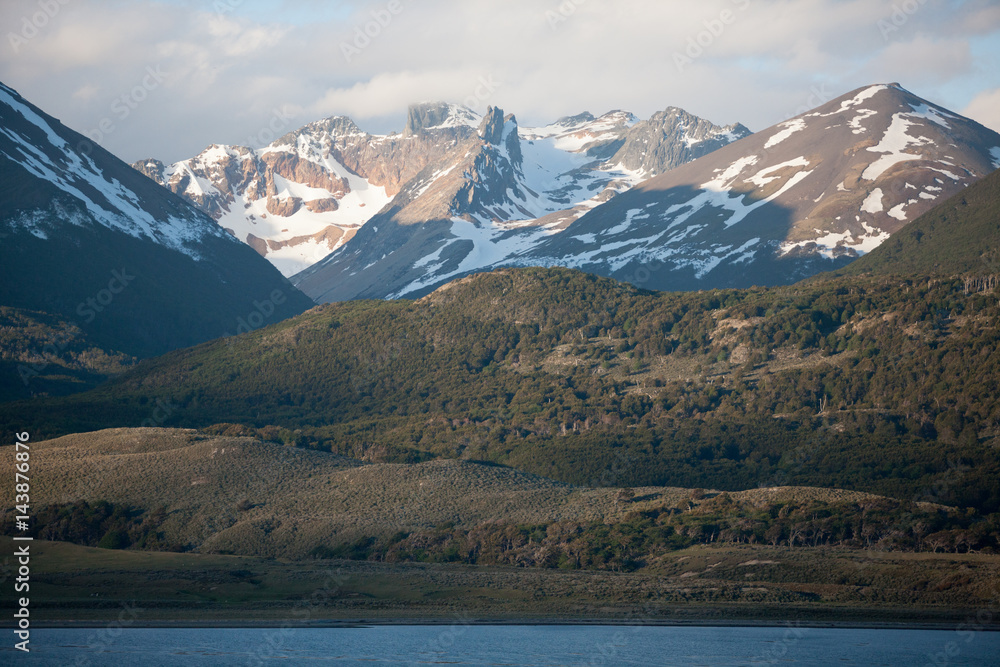 Tierra del Fuego, landscape of snowy and wooded mountains and ocean Tierra del Fuego, landscape of snowy and wooded mountains and ocean