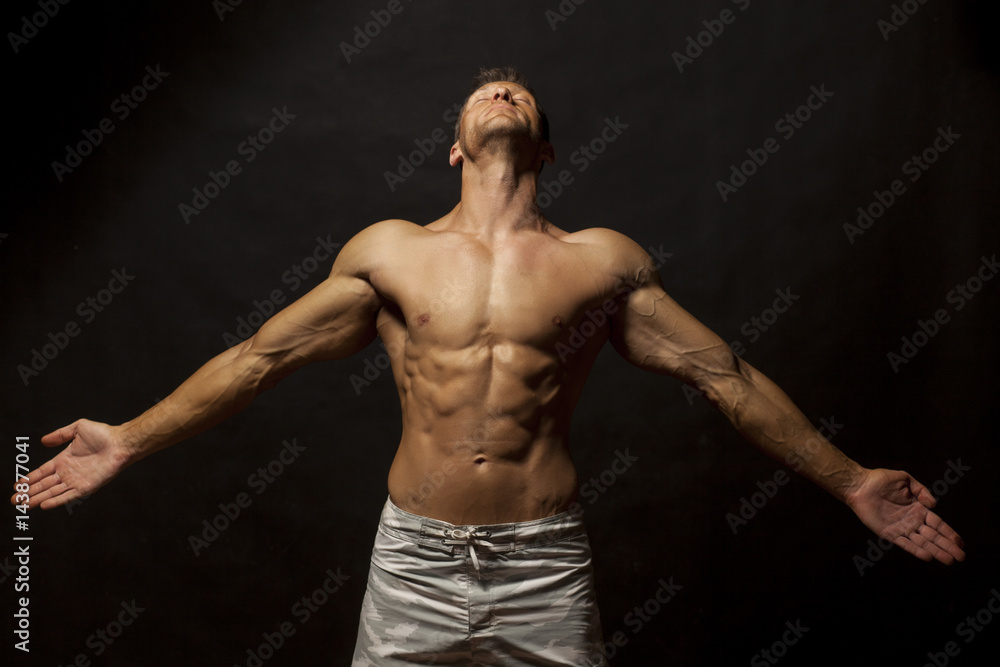 half-naked handsome and muscular young man posing on a dark background