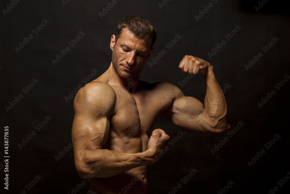 Fototapeta premium half-naked handsome and muscular young man posing on a dark background