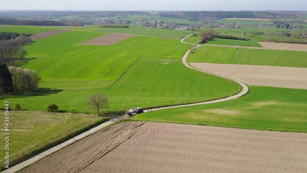 Aerial: tractor rides through the agrarian hilly fields in Somme-Leuze in Belgian Ardennes Aerial: tractor rides through the agrarian hilly fields in Somme-Leuze in Belgian Ardennes