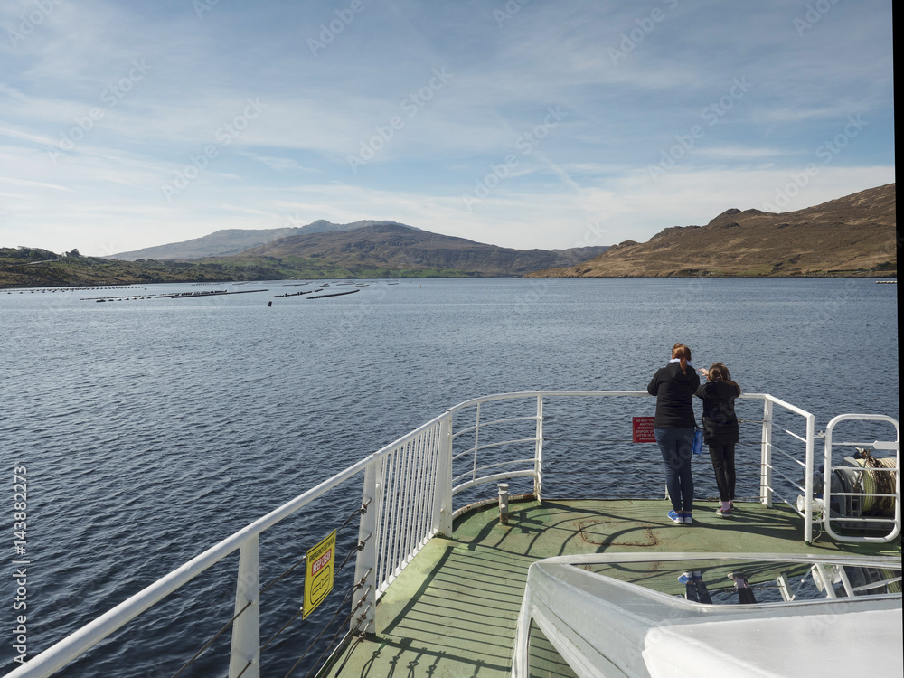 Fototapeta premium Mother and daughter looking at a mussels farm in a fjord from a bow of a cruise ship.