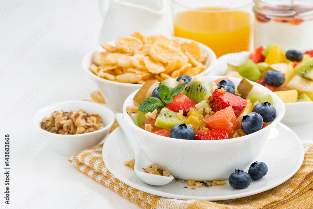 breakfast with fruit salad and corn flakes on white table breakfast with fruit salad and corn flakes on white table