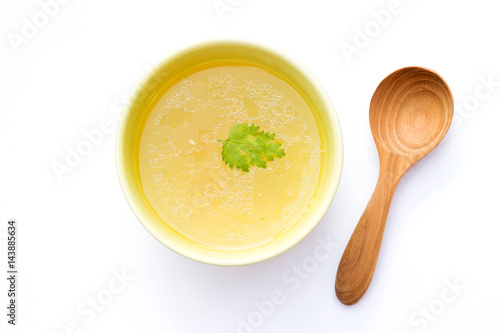 Bowl of chicken broth with wooden spoon isolated on white background photo