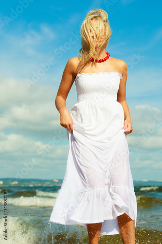 Blonde woman wearing dress walking in water © Voyagerix