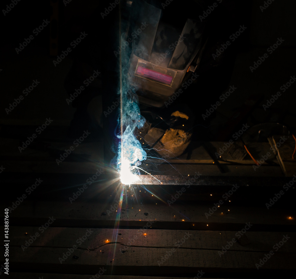 Worker with personal protective equipment and protective mask welding steel pipe in factory. Worker with personal protective equipment and protective mask welding steel pipe in factory.