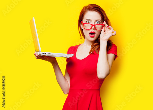 photo of beautiful young woman holding laptop on the wonderful yellow studio background