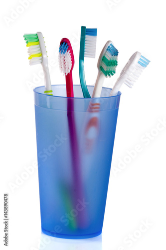 Toothbrushes in blue glass isolated on white background