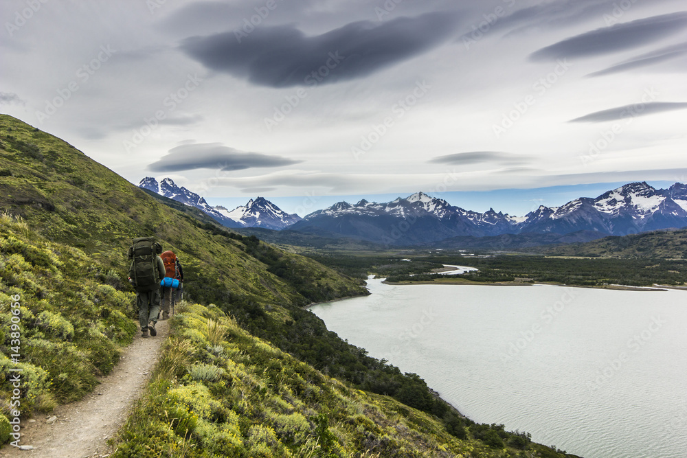 two men hiking in patagonia mountains, torres del paine with grey sky