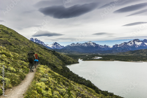two men hiking in patagonia mountains  torres del paine with grey sky