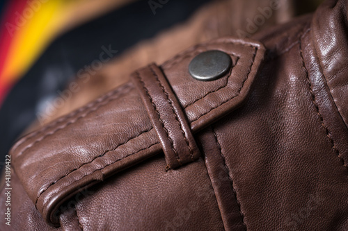 Brown leather jacket shoulder metal clasp button. Macro leather shoulder detail. Jacket on the rack