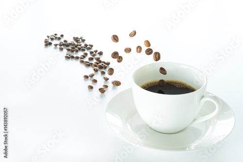 Coffee beans jumping into a white coffee cup