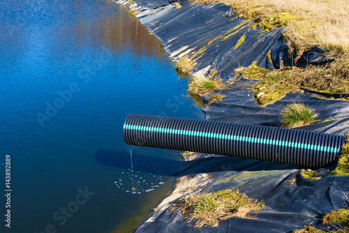 Landfill leachate pouring into pond from a black and blue pipe. Location Ronneby, Sweden. photo