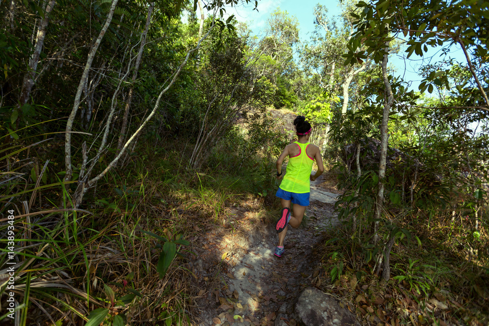 Young fitness woman trail runner running at forest mountain trail