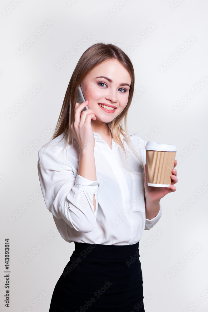 Young attractive business girl on a white background with coffee and phone Young attractive business girl on a white background with coffee and phone