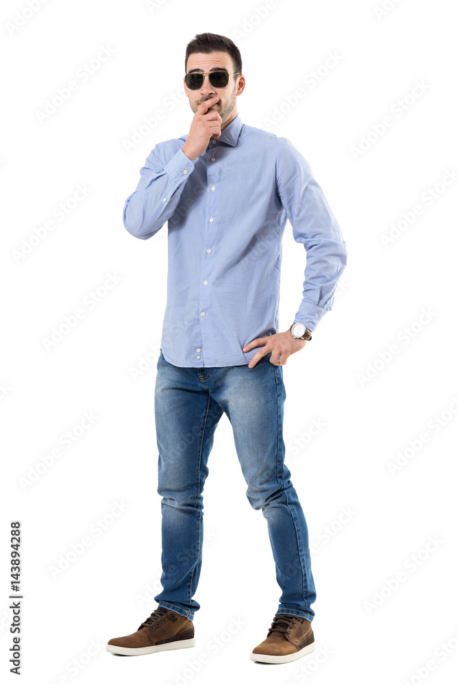 Puzzled worried young businessman with hands on chin looking at camera. Full body length portrait isolated over white background. Puzzled worried young businessman with hands on chin looking at camera. Full body length portrait isolated over white background.