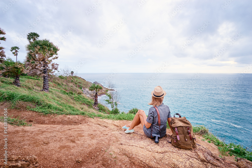 Travel concept. Young woman with camera and rucksack enjoying the sea view.