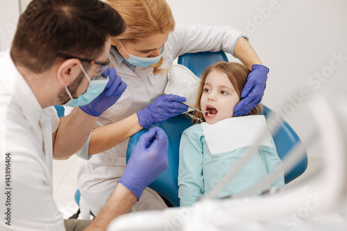 Two well trained colleagues working with little girl