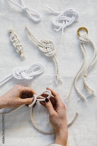 Hands creating yarn knots on tabletop