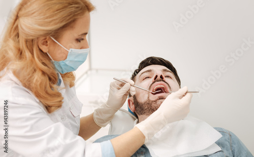 Productive talented dentist conducting a dental cleaning