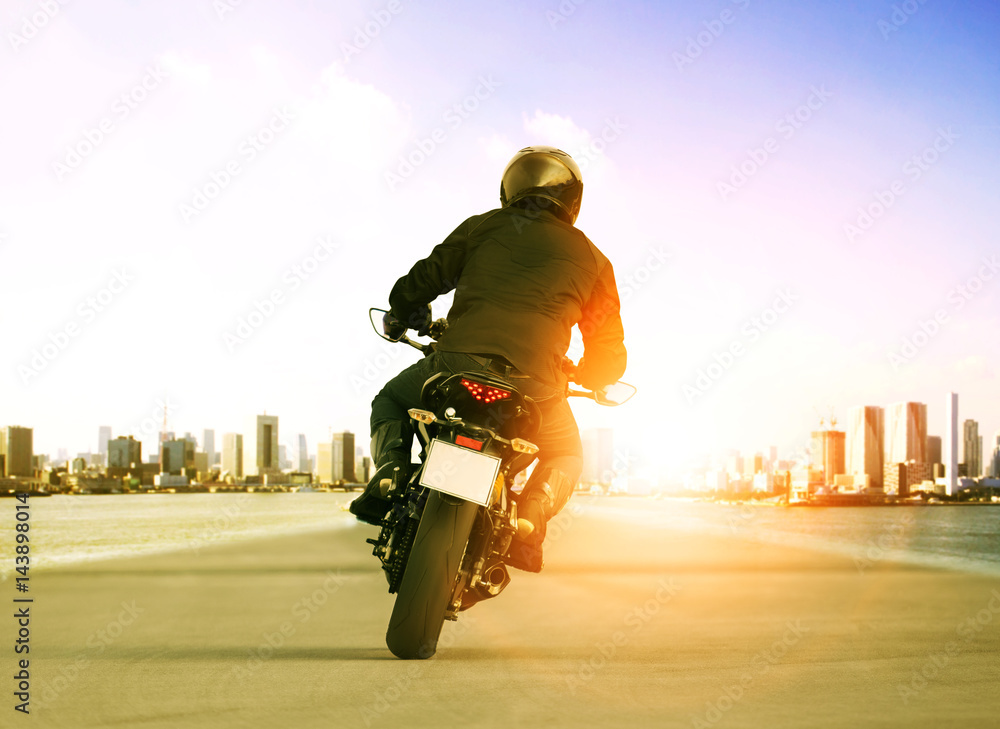 Obraz premium rear view of man riding motorcycle on urban traffic road for people leisure traveling theme