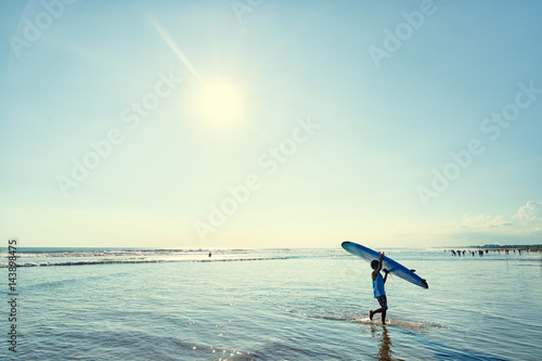 Hobby and vacation. Man carrying surf board on the sea shore.
