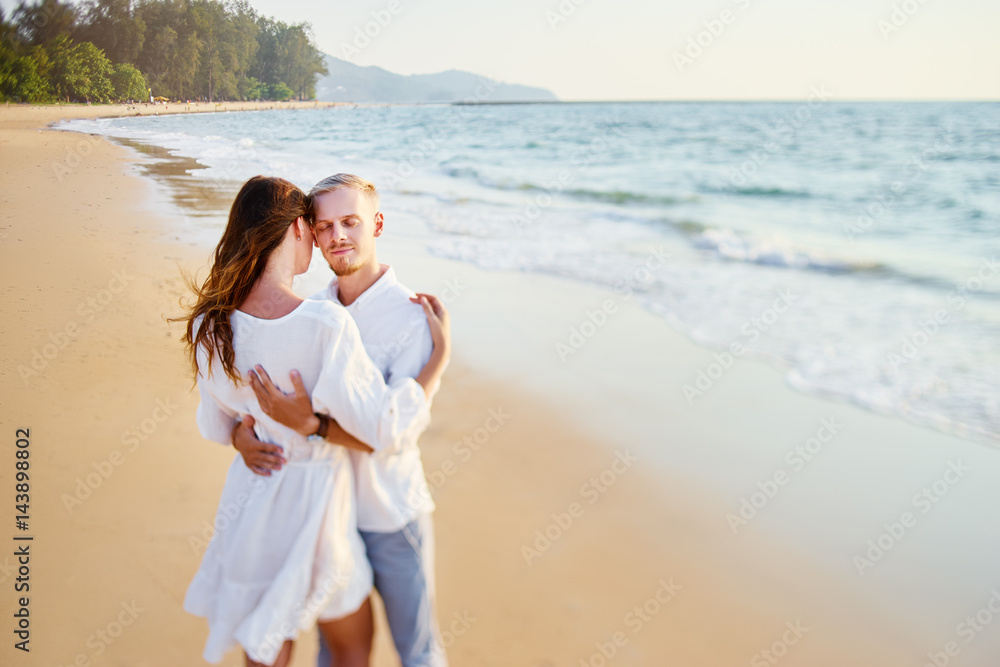 Romantic vacation. Love and tenderness. Young loving couple embracing on the sea sand beach.