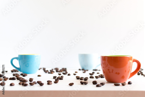 Colorful coffee cups on white table with beans