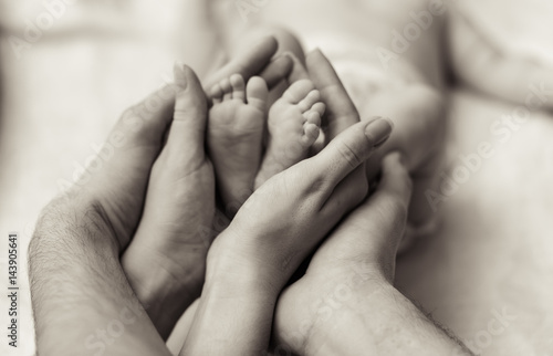 Mother holding tiny foot of newborn baby